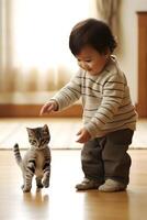 A toddler is happily playing with a kitten photo