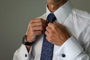 groom getting ready for his wedding and tightening his tie photo