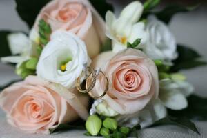 two golden wedding rings next to the bride's bouquet photo