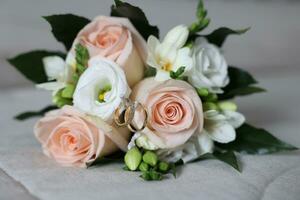 two golden wedding rings next to the bride's bouquet photo