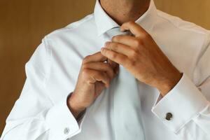 groom getting ready for his wedding and tightening his tie photo