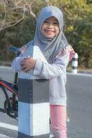 a girl smiling broadly holding a highway guardrail with the morning sun shining through photo