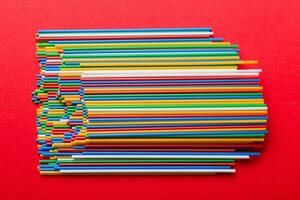 many multi-colored plastic tubes for cocktail on Colored background, top view photo
