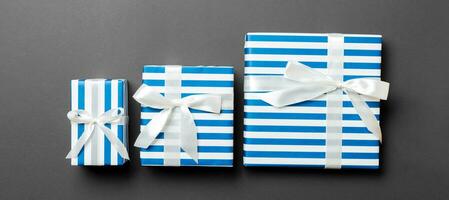 wrapped Christmas or other holiday handmade present in paper with White ribbon on black background. Present box, decoration of gift on colored table, top view photo