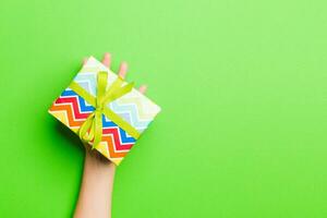 Top view of female hands holding christmas or other holiday handmade present box package in the palms, flat lay table background with copy space photo