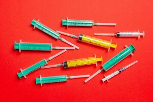 Top view of medical syringes with needles at red background with copy space. Injection treatment concept photo