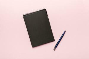 school notebook on a colored background, spiral black notepad on a table Top view photo