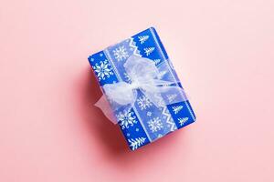 Top view Christmas present box with white bow on pink background with copy space photo