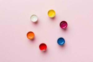 jars with gouache of different colors on Colored background. hobby painting. Top view with empty space. workplace for creativity. home teaching concept drawing photo