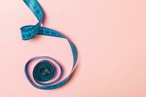 Tangled measuring tape with space for your idea. Sewing and tailor concept on pink background photo