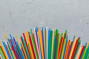 Heap of colorful plastic drinking straws on Colored background, flat lay. Copy Space for text photo