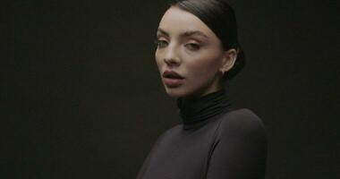 portrait tournage de une Jeune femme dans une studio sur une noir Contexte. lent mouvement. video