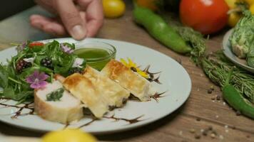 Chicken roll with spinach nicely served on a plate with greens, flower decorations and green oil video