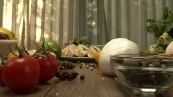 frisch Gemüse im das Box auf das Küche Tabelle Kamera Nahansicht. Flaschen mit Essig und Öl und Pfeffer Shaker Mühle auf das zurück video