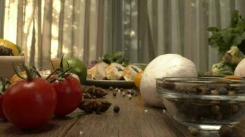 Fresh vegetables in the box on the kitchen table camera close-up. Bottles with vinegar and oil and pepper shaker mill on the back video