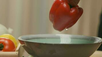 professioneel chef bereidt zich voor en bezuinigingen rood klok peper. dichtbij omhoog langzaam beweging video