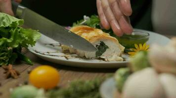 servendo pollo rotolo con spinaci. Là siamo verdura e verde olio su il piatto. avvicinamento con mani, lento movimento. video