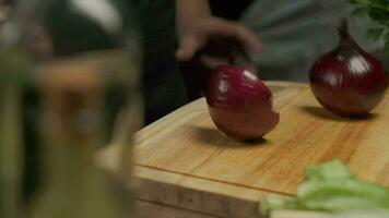 professionnel chef prépare et coupes rouge oignon. proche en haut lent mouvement video