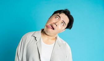 retrato de un asiático chico posando en un azul antecedentes foto