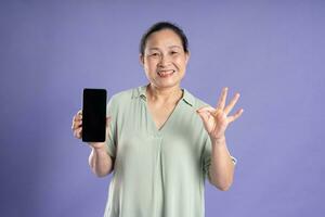 Gangang middle-aged Asian female portrait posing on purple background photo