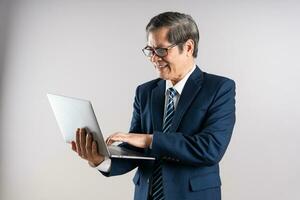 Portrait of an elderly Asian businessman, posing on a blue background photo