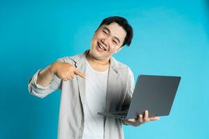 Image of Asian man using laptop on blue background photo