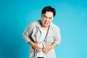 Image of Asian man having health problems, isolated on blue background photo