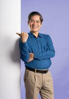 portrait of middle aged asian business man posing on purple background photo