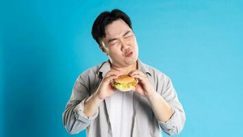 retrato de asiático hombre comiendo rápido comida en azul antecedentes foto