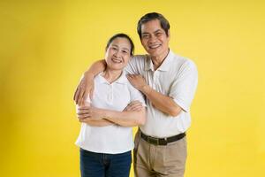 retrato de medio Envejecido asiático Pareja posando en amarillo antecedentes foto