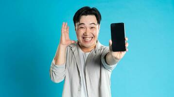 Image of Asian man using phone on blue background photo