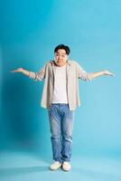 Full body image of Asian man posing on blue background photo