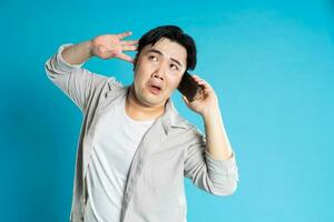 Image of Asian man using phone on blue background photo