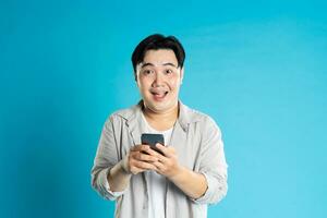 Image of Asian man using phone on blue background photo