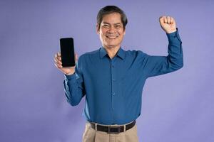 retrato de medio Envejecido asiático negocio hombre posando en púrpura antecedentes foto