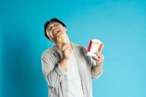 retrato de asiático hombre comiendo rápido comida en azul antecedentes foto