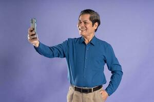 portrait of middle aged asian business man posing on purple background photo