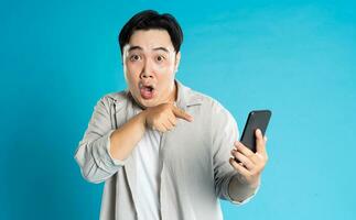 Image of Asian man using phone on blue background photo