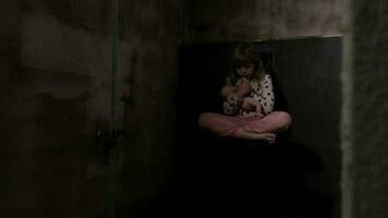 uma jovem menina sentado em a chão com dela boneca dentro a Sombrio video