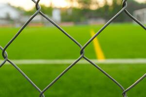 A soccer field view from outside the fence, focusing on the fence. After some edits. photo