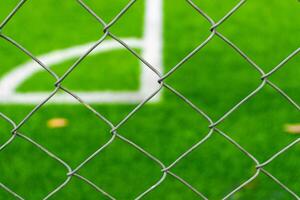A soccer field view from outside the fence, focusing on the fence. After some edits. photo