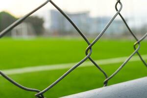 A soccer field view from outside the fence, focusing on the fence. After some edits. photo