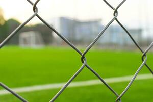 A soccer field view from outside the fence, focusing on the fence. After some edits. photo