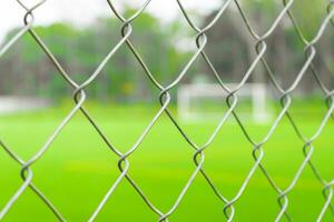 A soccer field view from outside the fence, focusing on the fence. After some edits. photo