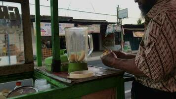 Magelang,Indonesia.09-23-2023.a man is making apple juice with a manual blender. video