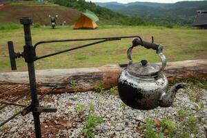 An old and dirty kettle used to boil water in the campsite. photo