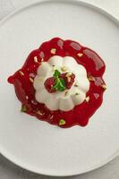 Vertical orientation panna cotta with raspberry syrup, pistachios, berries and mint photo