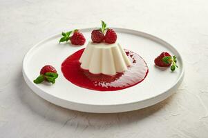 Panna cotta with raspberry syrup, pistachios,berries and mint photo