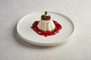 Panna cotta with raspberry syrup, pistachios,berries and mint photo