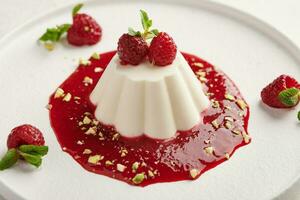 Panna cotta with raspberry syrup, pistachios,berries and mint photo